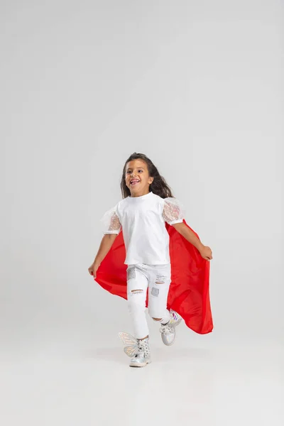 Kleine superheld. Klein schattig blank meisje in een rode cape geïsoleerd over witte studio achtergrond. Volledig portret — Stockfoto