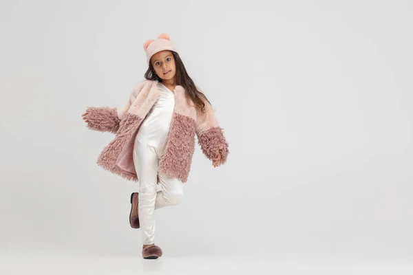 Un petit mannequin. Une jolie fille préscolaire souriante en manteau élégant et chapeau posant isolé sur fond de studio blanc. — Photo