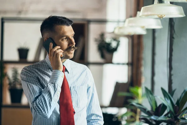 One young businessman, office worker, manager with smartphone. Modern office interior — Fotografia de Stock