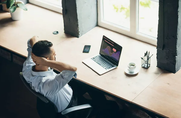 Comparison of graphs. One young businessman, office worker with laptop. Business, working process concept. View from above — Fotografia de Stock