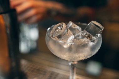 Close up. One glass for margarita cocktail or shampagne filled with pure ice standing on bar counter
