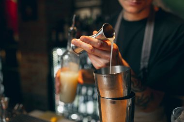 Close up image. One bartender preparing an alcohol drink in cocktail shaker enjoying his job.