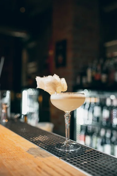 One glass filled with alcohol cocktail or shampagne decorated with cotton candy standing on bar counter — Foto de Stock