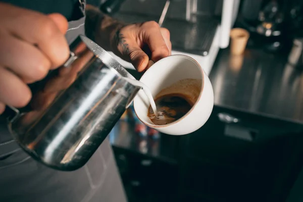 Barista gießt Milch in eine Tasse Kaffee, süßen Cappuchino oder Latte. Bild aus nächster Nähe — Stockfoto