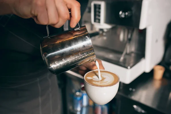 Barista gießt Milch in eine Tasse Kaffee, süßen Cappuchino oder Latte. Bild aus nächster Nähe — Stockfoto