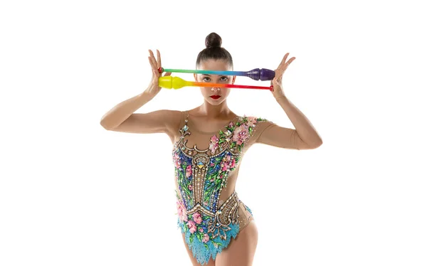 Hermosa joven gimnasta rítmica femenina posando con palos de colores en sus manos aisladas sobre fondo blanco. — Foto de Stock