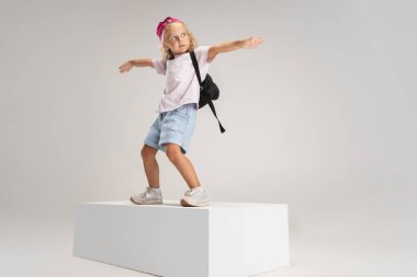 Dans eden hip-hop. Beyaz stüdyo arka planında izole edilmiş günlük giysiler içinde küçük bir anaokulu beyaz kız portresi.