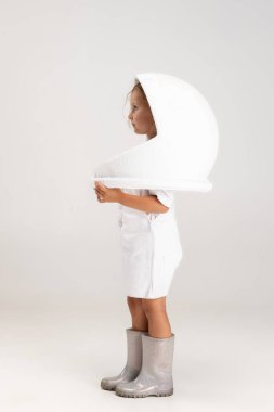 Beyaz stüdyo arka planında izole edilmiş büyük kasklı küçük beyaz kız anaokulu beyaz portresi.