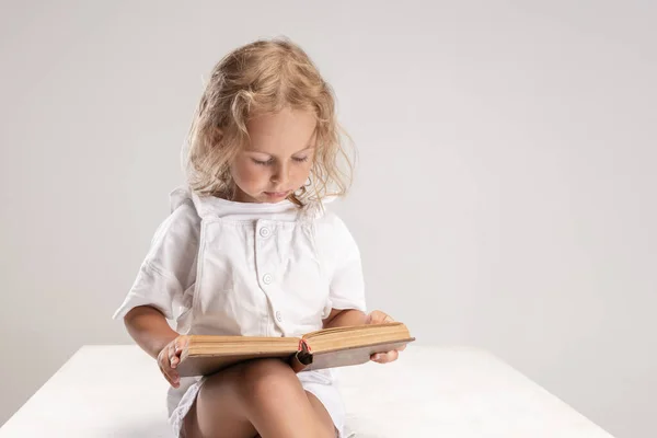 ポートレートの小さなかわいいです白人の女の子読書本座って孤立した上にホワイトスタジオの背景. — ストック写真
