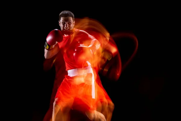 Első nézet egy profi férfi bokszoló mozgásban, akció a fekete stúdió háttér vegyes fények. — Stock Fotó