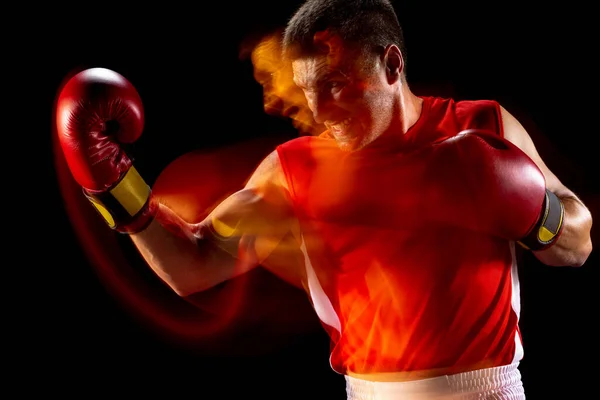 Visão lateral retrato de um boxeador masculino profissional em sportswear vermelho e luvas em fundo estúdio preto em luzes mistas. — Fotografia de Stock