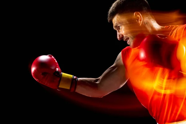 Stomp, uppercut. Gesneden portret van professionele mannelijke bokser training op zwarte studio achtergrond in gemengd licht. — Stockfoto