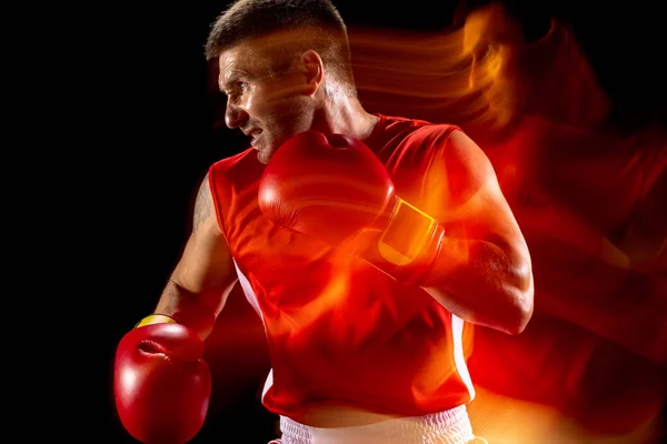 Gesneden portret van professionele mannelijke bokser training op zwarte studio achtergrond in gemengd licht. Rood en zwart — Stockfoto