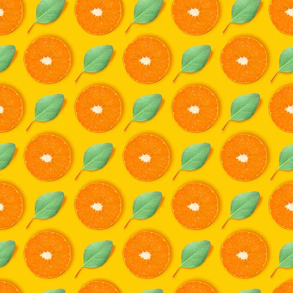 Modern art collage. Juicy slices of orange and small green leaves arranged in even rows over bright yellow background. — Stock Photo, Image