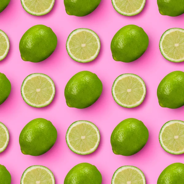 Cítricos agrios. Rodajas y limas verdes enteras dispuestas sobre fondo rosa brillante. — Foto de Stock