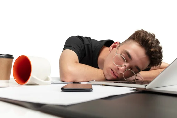 Portrait of one young man, tired student sleeping at table on white studio background. — Zdjęcie stockowe