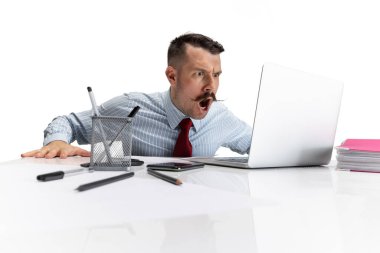Beyaz arka planda oturan genç bir beyaz adam, ofis çalışanı dizüstü bilgisayar monitörüne bakıyor..