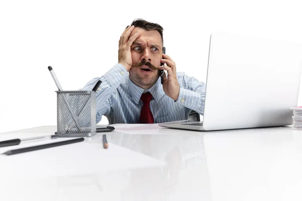 Um jovem caucasiano, trabalhador de escritório a olhar para a tela do portátil no fundo branco. Parece chateado, esquisito. — Fotografia de Stock