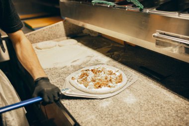 Şef lezzetli mantarlı pizzayı pişirmeden önce yuvarlak hamura koyar. Lezzetli görünüyor.
