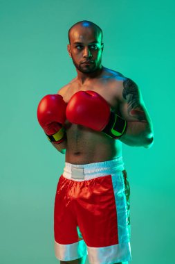 Kırmızı eldivenli profesyonel bir erkek boksörün dikey portresi mavi yeşil arka planda neon ışıkta izole edilmiş..