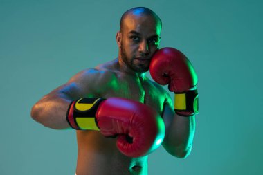 Yakın plan. Kırmızı eldivenli profesyonel bir erkek boksör, neon ışıklı mavi arka planda egzersiz yapıyor..