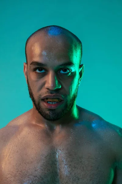 Närbild porträtt av en professionell manlig boxare med tandskydd isolerad över blå grön bakgrund i neon ljus. — Stockfoto