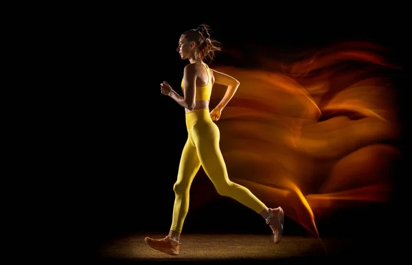 Fiatal nő, női atléta edzés elszigetelt fekete stúdió háttér vegyes neon fények. Oldalnézet — Stock Fotó