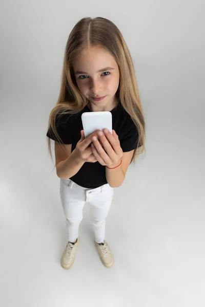 My phone. One little screaming school girl holding smartphone isolated over white studio background. — Stock Photo, Image