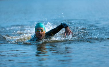 Nehirlerde yüzen profesyonel bir triatlet. Yüzme ekipmanı giyen bir adam yaz günlerinde plajda triatlon antrenmanı yapıyor..