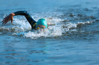 Nehirlerde yüzen profesyonel bir triatlet. Yüzme ekipmanı giyen bir adam yaz günlerinde plajda triatlon antrenmanı yapıyor..