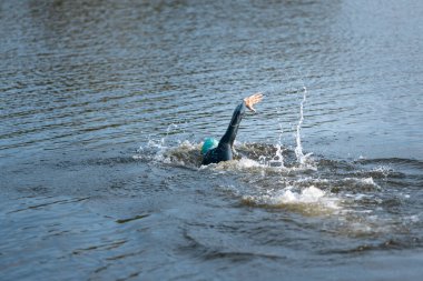 Nehirlerde yüzen profesyonel bir triatlet. Yüzme ekipmanı giyen bir adam yaz günlerinde plajda triatlon antrenmanı yapıyor..