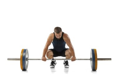 Beyaz arka planda izole edilmiş bir ağırlıkla spor kıyafetli bir adamın tam boy portresi.
