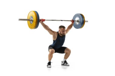 Beyaz arka planda izole edilmiş bir ağırlıkla spor kıyafetli bir adamın tam boy portresi.