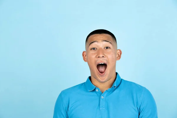 Close-up retrato de jovem sorrindo bonito asiático homem em roupas casuais isolado sobre luz azul estúdio fundo. — Fotografia de Stock