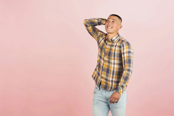 Retrato de jovem sorrindo bonito asiático homem em uma camisa xadrez isolado sobre luz rosa estúdio fundo. — Fotografia de Stock