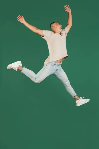 De cuerpo entero retrato de joven guapo asiático saltando aislado sobre oscuro verde estudio fondo. — Foto de Stock