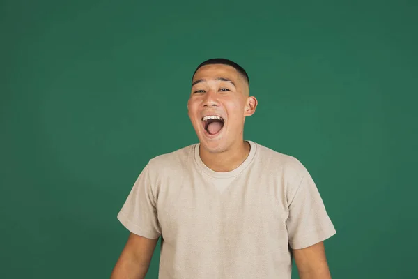 Portrait of young handsome asian man laughing, having fun isolated over dark green studio background. — 스톡 사진