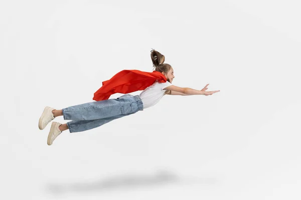 Πορτρέτο του εφήβου καυκάσιου κοριτσιού του σχολείου με casual ρούχα και κόκκινη κάπα που πετούν απομονωμένη πάνω από λευκό φόντο στούντιο. Πλευρική άποψη — Φωτογραφία Αρχείου