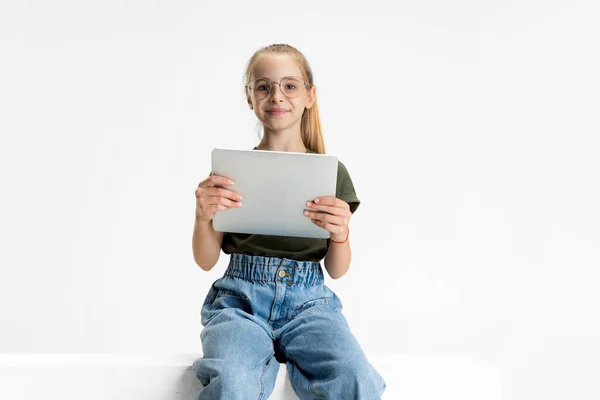 One smart teen school caucasian girl in casual clothes and glasses holding tablet isolated over white studio background. — Stock Photo, Image