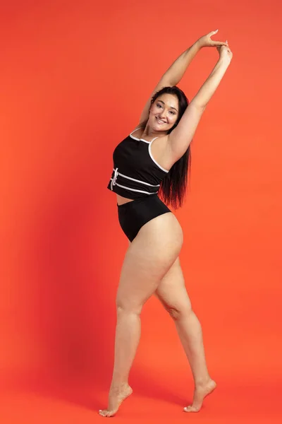 Jovem bela mulher gorda em roupa interior preta no fundo laranja — Fotografia de Stock