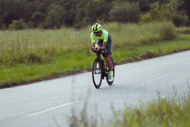 Açık yolda bisiklet süren genç bir erkek triatloncu. Profesyonel sporcu aydınlık yaz gününde triatlona katılır.