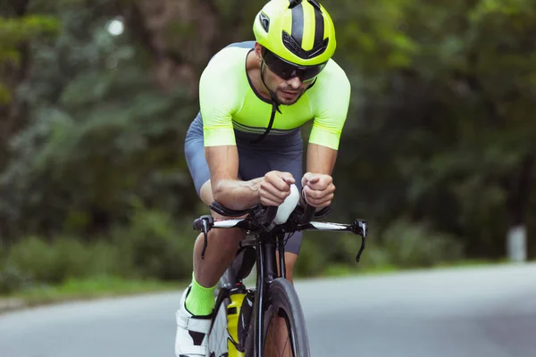 Junge männliche Triathleten auf dem Fahrrad auf offener Straße. Profisportler treibt Triathlon bei strahlendem Sommertag — Stockfoto