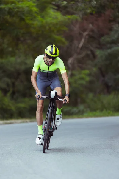 Junge männliche Triathleten auf dem Fahrrad auf offener Straße. Profisportler treibt Triathlon bei strahlendem Sommertag — Stockfoto