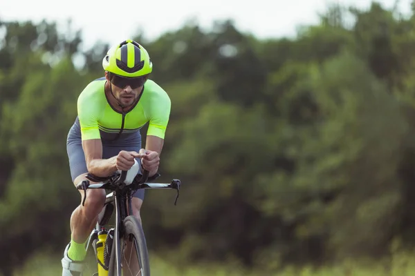 Junge männliche Triathleten auf dem Fahrrad auf offener Straße. Profisportler treibt Triathlon bei strahlendem Sommertag — Stockfoto