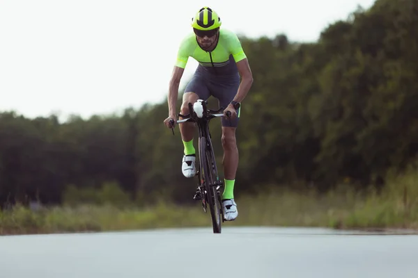 Junge männliche Triathleten auf dem Fahrrad auf offener Straße. Profisportler treibt Triathlon bei strahlendem Sommertag — Stockfoto