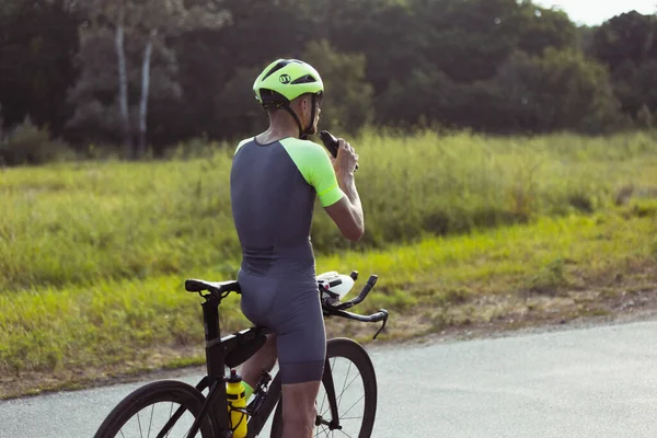 Junge männliche Triathleten auf dem Fahrrad auf offener Straße. Profisportler treibt Triathlon bei strahlendem Sommertag — Stockfoto