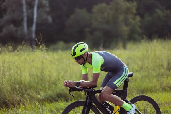 Junge männliche Triathleten auf dem Fahrrad auf offener Straße. Profisportler treibt Triathlon bei strahlendem Sommertag — Stockfoto