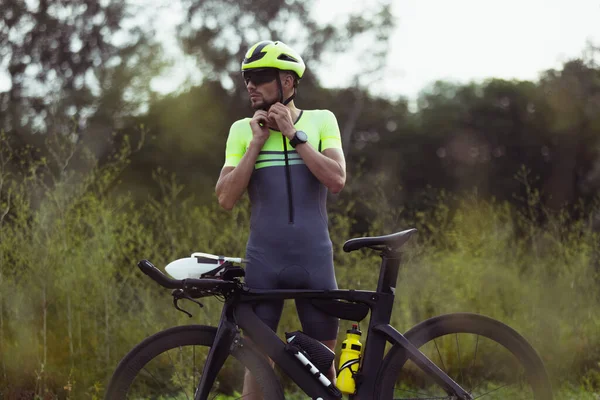 Junge männliche Triathleten auf dem Fahrrad auf offener Straße. Profisportler treibt Triathlon bei strahlendem Sommertag — Stockfoto