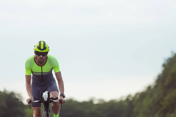 Junge männliche Triathleten auf dem Fahrrad auf offener Straße. Profisportler treibt Triathlon bei strahlendem Sommertag — Stockfoto