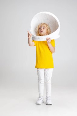 Beyaz stüdyo arka planında izole edilmiş kaskla poz veren anaokulu çocuğunun portresi..